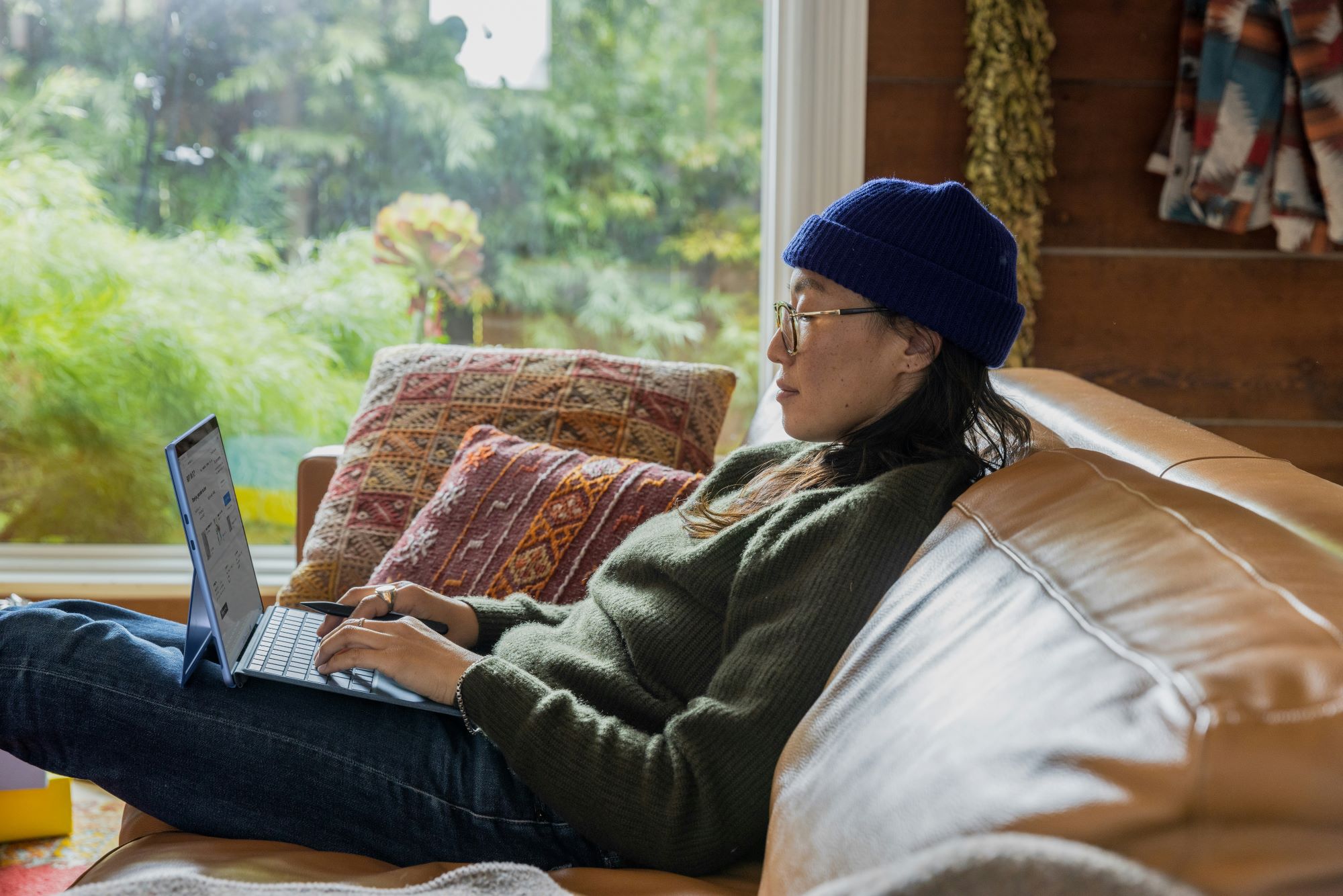 A person in a hoodie working on a laptop in a cozy space, symbolizing emotional self-awareness and healing from anxious attachment.