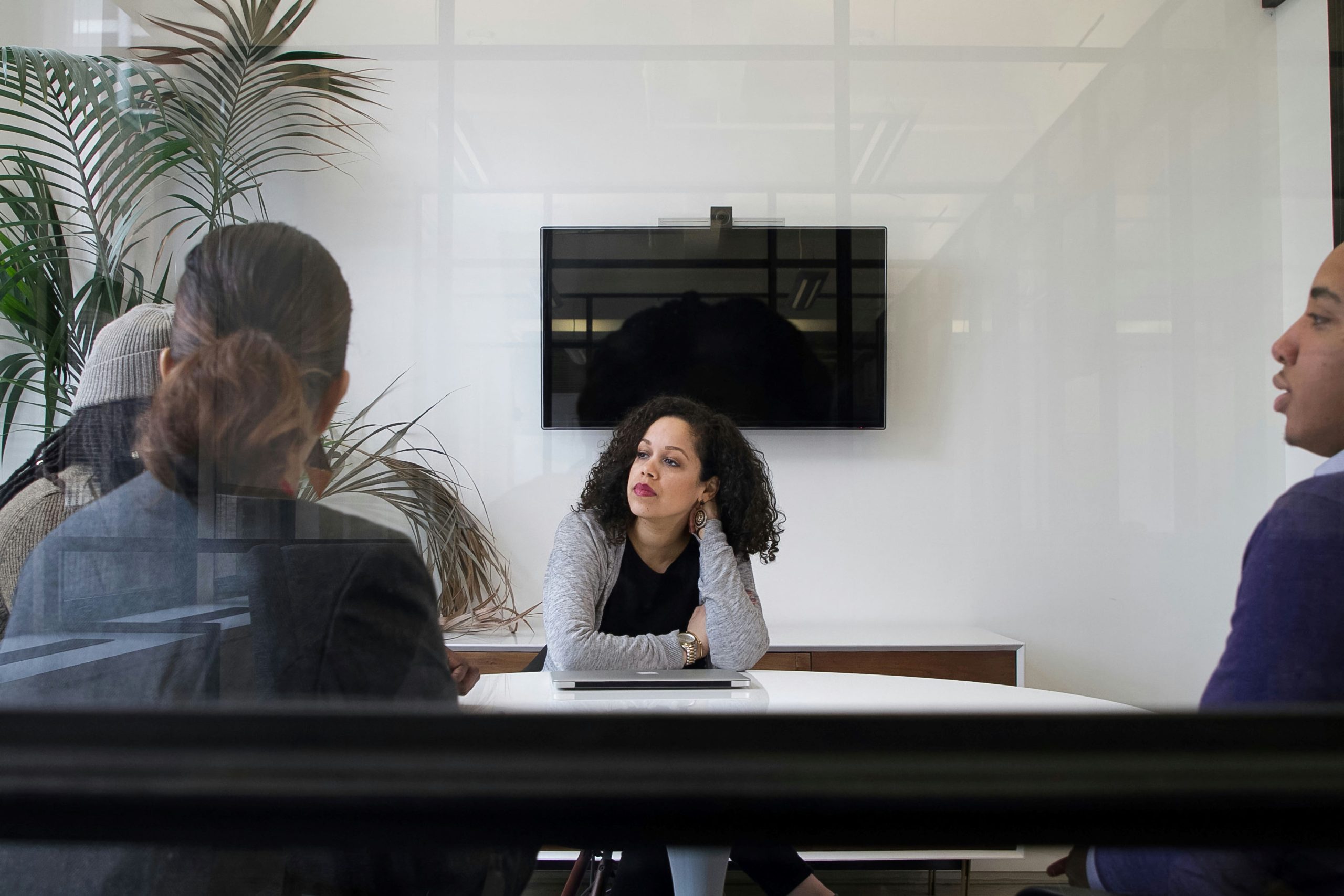 A woman appears deep in thought during a meeting, reflecting emotional exhaustion or contemplation, symbolizing workplace dissatisfaction or burnout.